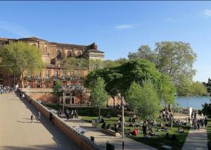 een groep mensen die in een park voor een gebouw zitten bij Horizon Paisible - Piscine et parking ! in Toulouse
