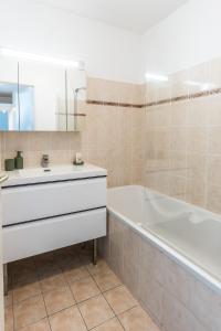 een badkamer met een bad, een wastafel en een bad tubermottermott bij Horizon Paisible - Piscine et parking ! in Toulouse +41 foto's
