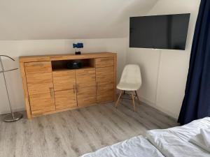 a bedroom with a dresser with a television and a chair at Villa Ostseebrise in Trent