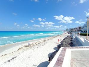 a beach with people on the sand and the ocean at Comoda Suite Cancun - BEACH CONDO - 6PX in Cancún
