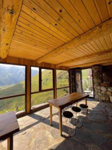 a wooden table and stools in a room with windows at Guesthouse Kvavlo in Kvavlo