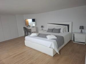 a white bedroom with a large bed and a desk at Casa do Diniz in Travassos +26 photos