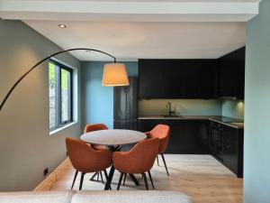 a kitchen with a table with orange chairs and aendant light at Granli-Apartment in Stryn
