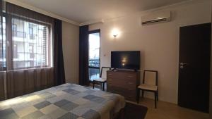 a bedroom with a bed and a tv and a window at Premium Oasis Beach Club Apartment in Lozenets