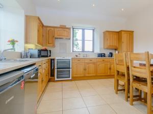 a kitchen with wooden cabinets and a table and chairs at Mulberry Cottage in North Wootton