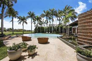 a swimming pool with palm trees and a building at Casa del Sol in La Romana
