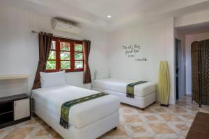 a hotel room with two beds and a window at Samma Karuna Beach & Wellness Resort - Intoxicants free in Haad Chao Phao