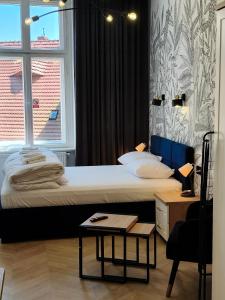 a bedroom with a bed with a table and a window at Drzewna Apartamenty-Żeromskiego, Stare Miasto in Zielona Góra