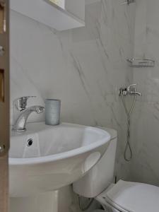 a white bathroom with a sink and a toilet at Rozy Studios in Pefki