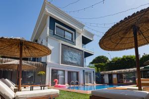 a building with a swimming pool and two umbrellas at Mistral Alaçatı Hotel in Çeşme