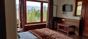 a bedroom with a bed and a window and a television at Teyser Holiday Home in Leh