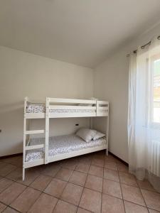 two white bunk beds in a room with a window at Casa Chiara in Mandello del Lario