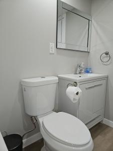 a white bathroom with a toilet and a mirror at Jimmy in Winnipeg +11 photos