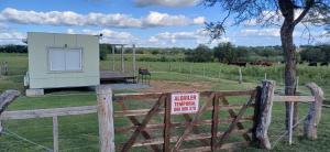 a smallshed in a field with a sign on a fence at La Demorada in Mercedes