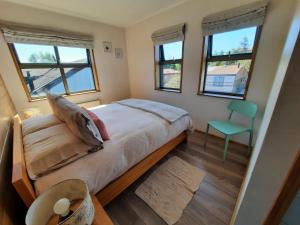 a bedroom with a bed and a chair and windows at Edificio Guadalauquen in Valdivia +71 photos