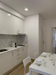 Una cocina con gabinetes blancos y una mesa y sillas. en Casa Rabiosa, en Nazaré 5 fotos más