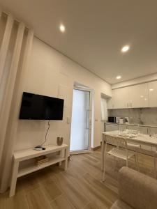 Una sala de estar con una mesa y un televisor en la pared. en Casa Rabiosa, en Nazaré