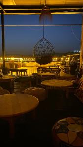 a patio with tables and chairs and a chandelier at night at Nova surf house in Tamraght Oufella