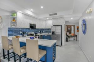 a blue and white kitchen with a counter and chairs at 2 Bedroom Oceanview Beachfront Condo Jaco Beach in Jacó