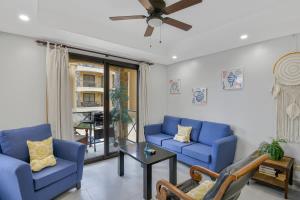 a living room with blue couches and a ceiling fan at 2 Bedroom Oceanview Beachfront Condo Jaco Beach in Jacó +19 photos