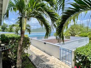 a palm tree in front of a house with the ocean at La p’tite barque Antillaise in Deshaies