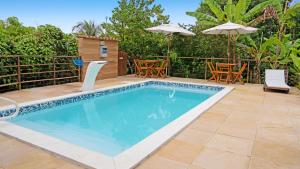 uma piscina com cadeiras e guarda-sóis num quintal em Piscina Aquecida, Jacuzzi, internet veloz, no centro de Serra Grande - Flat Céu - Vila Pitangueira em Serra Grande