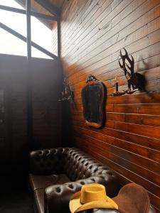 eine braune Ledercouch mit einem Hut an der Wand in der Unterkunft Cabana Black Wood in Camanducaia