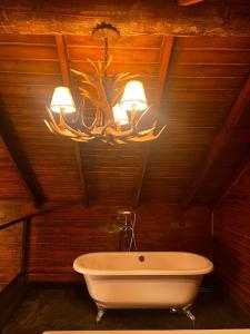 ein Badezimmer mit einer großen weißen Badewanne und einem Kronleuchter in der Unterkunft Cabana Black Wood in Camanducaia