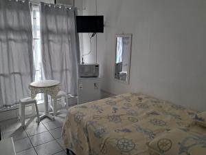 Un dormitorio con una cama, una mesa y una silla. en Pousada Centralmar, en Florianópolis