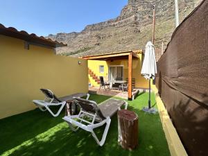 a patio with chairs and an umbrella and a table at SUNNY CARMELITO DELUXE in Mogán