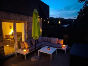 a patio with a couch and an umbrella and a table at Studio moderne à proximité des 7 Meuses in Profondeville