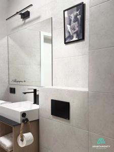 ein Badezimmer mit Waschbecken und einem Fernseher an der Wand in der Unterkunft APARTAMENTY SZYNDZIELNIA 2 POKOJE & BALKON & PARKING & ROWEROWNIA WORKATION Home OFFICE - NOWA NAJLEPSZA BAZA WYPADOWA W BESKIDY in Bielsko-Biała