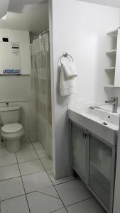 a white bathroom with a sink and a toilet at Main Street Suites Nanton in Nanton +12 photos