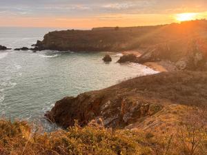 a view of a beach with the sun setting over the water at Coup de cœur ! Maisonnette neuve à 300 m du port et de la plage in L'Ile d'Yeu