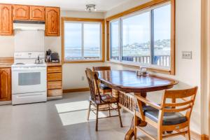 a kitchen with a table and chairs and windows at Harbor View Cottage A in Gold Beach