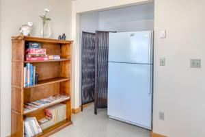 a kitchen with a refrigerator and a book shelf at Harbor View Cottage A in Gold Beach