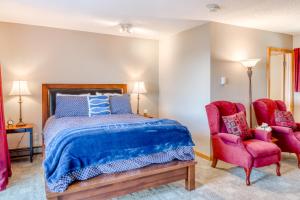 a bedroom with a bed and two red chairs at Harbor View Cottage A in Gold Beach