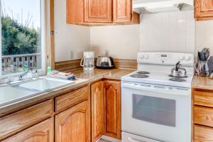 a kitchen with wooden cabinets and a white stove top oven at Harbor View Cottage A in Gold Beach +15 photos