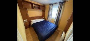 a small bed in a small room with a window at Bungalow TORNADO climatisé avec 3 chambres in Saint-Laurent