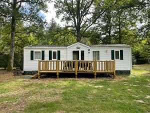 a white tiny house with a porch and a deck at Bungalow TORNADO climatisé avec 3 chambres in Saint-Laurent