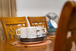 a table with two mugs and plates on it at 3 Bedroom Luxury Stay in Accra-The Kwaba Villa in Tema +6 photos