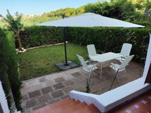 a white table and chairs under an umbrella at Del jardín a la playa in Islantilla