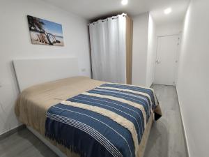 a bedroom with a bed with a blue and white striped blanket at Del jardín a la playa in Islantilla +9 photos