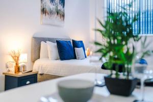 Un dormitorio con una cama con almohadas azules y una planta en Old Bank Apartment Complex, en Bolton