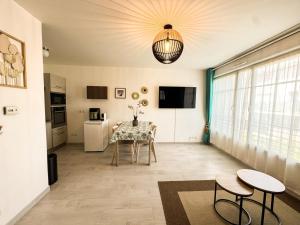 a dining room with a table and chairs and a chandelier at Appartement Magnolia 40m2, wifi gratuit et parking payant in Montévrain
