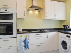 a kitchen with white cabinets and a washer and dryer at Puffin Cottage in Bempton