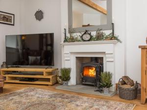 a living room with a fireplace and a tv at Harpers Cottage in Barrowford