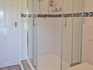 a shower with a glass door in a bathroom at Ty Capel Gosen in Trefor