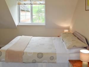 ein Bett in einem Schlafzimmer mit Fenster in der Unterkunft Bluebell Cottage in Wootton Fitzpaine