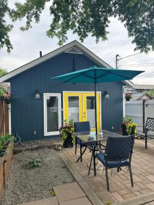 a blue shed with a table and chairs and an umbrella at K STREET CARRIAGE HOUSE Studio in Penticton